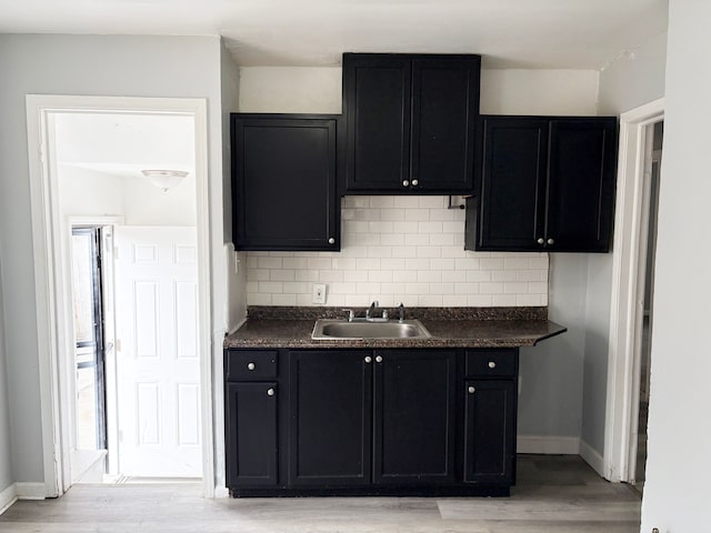 kitchen with a sink, decorative backsplash, and dark countertops