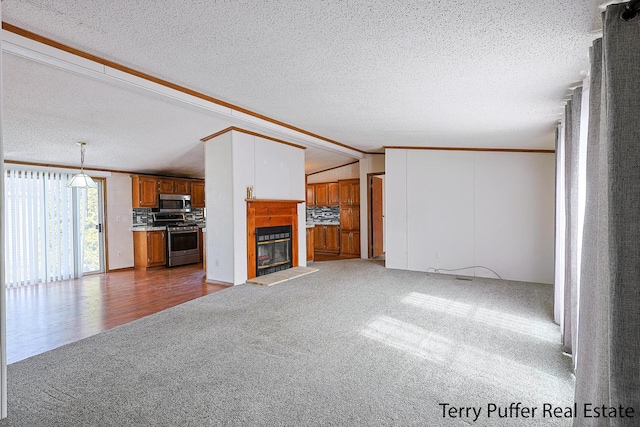 unfurnished living room with carpet floors, a glass covered fireplace, vaulted ceiling, and crown molding