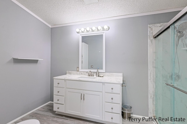 full bath with a textured ceiling, wood finished floors, vanity, ornamental molding, and a marble finish shower