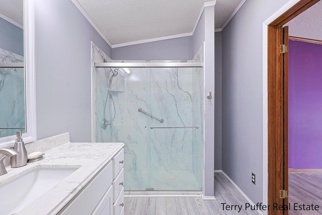 bathroom with a textured ceiling, a marble finish shower, wood finished floors, and vanity