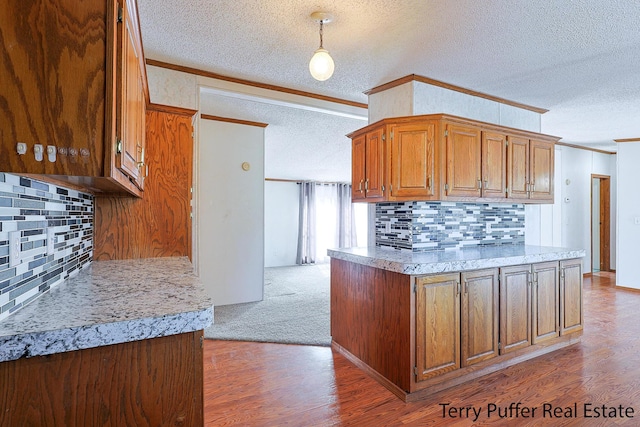 kitchen with light wood-type flooring, a textured ceiling, brown cabinets, and crown molding