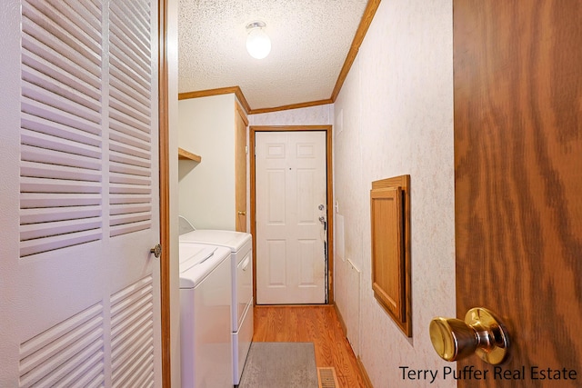 laundry room featuring light wood finished floors, washing machine and clothes dryer, visible vents, ornamental molding, and laundry area