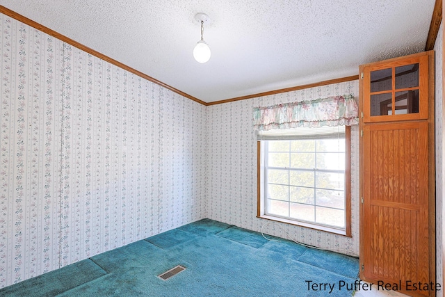 spare room with wallpapered walls, visible vents, and a textured ceiling