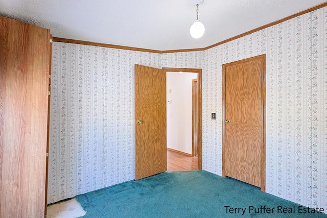 unfurnished bedroom with ornamental molding, carpet floors, a textured ceiling, and wallpapered walls