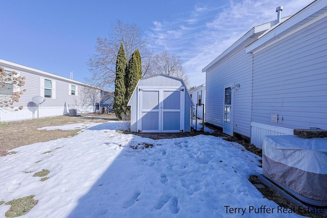 snowy yard with an outbuilding, central AC, and a storage unit