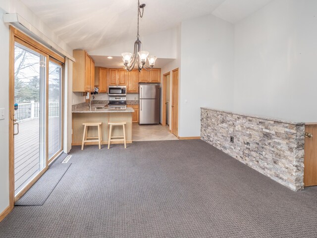 kitchen with light colored carpet, lofted ceiling, appliances with stainless steel finishes, light countertops, and a sink