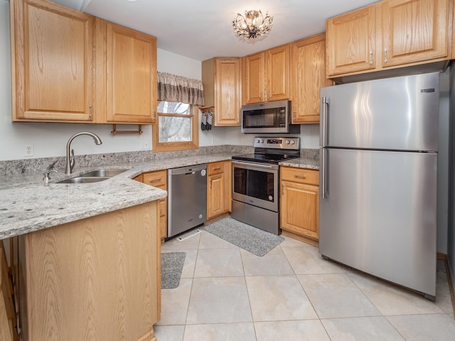 kitchen featuring light stone countertops, stainless steel appliances, light brown cabinets, a sink, and light tile patterned flooring