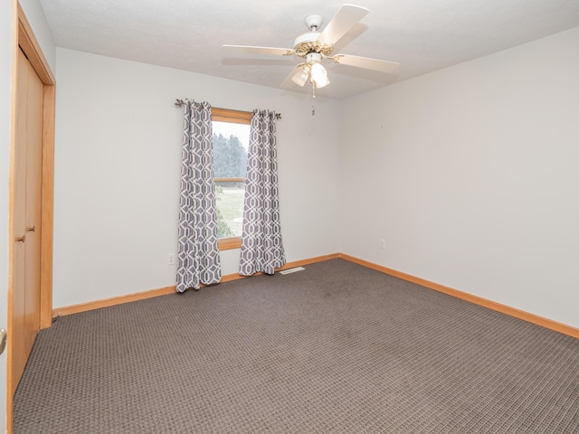 carpeted empty room featuring ceiling fan and baseboards