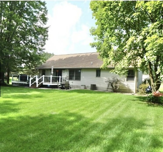 rear view of house with central AC and a yard