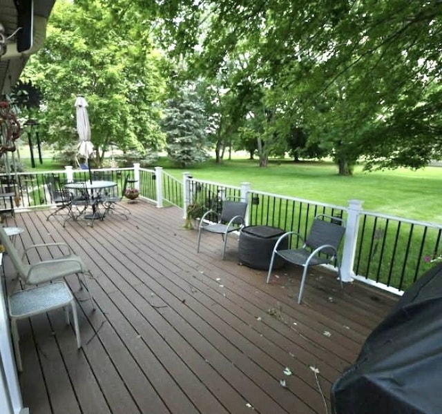 wooden deck featuring outdoor dining space and a yard