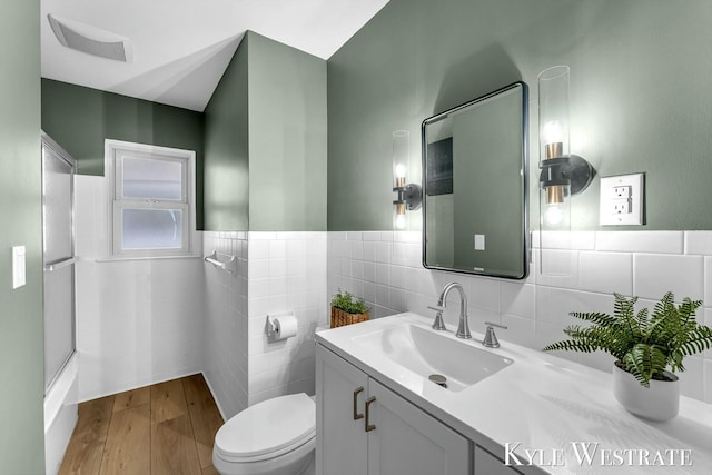 bathroom with tile walls, visible vents, toilet, wainscoting, and vanity