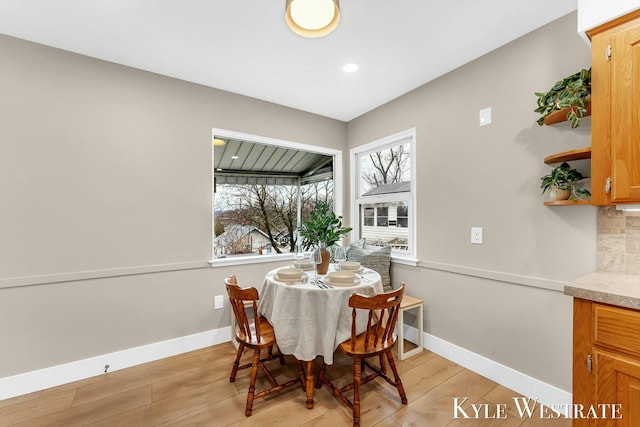 dining area with light wood-type flooring, plenty of natural light, and baseboards