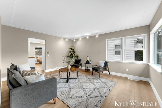 living room with light wood finished floors, rail lighting, visible vents, and baseboards