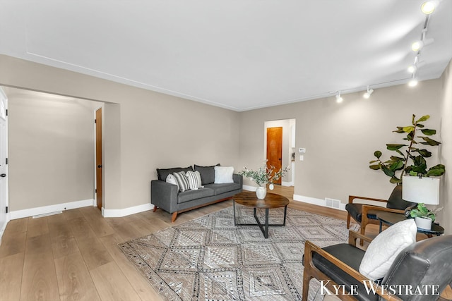 living area featuring wood-type flooring, visible vents, and baseboards