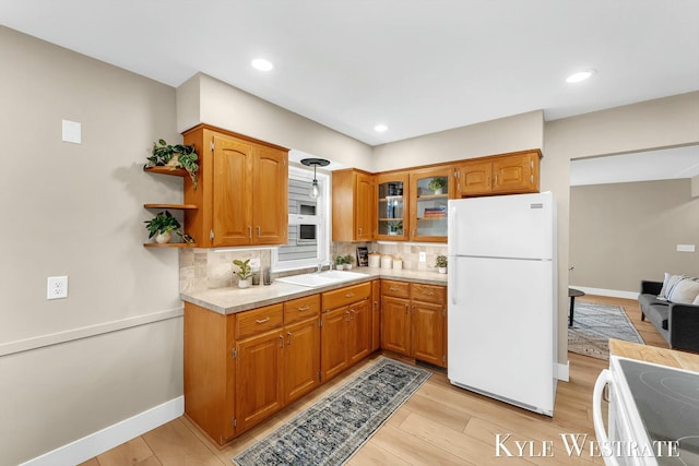 kitchen with brown cabinets, white appliances, light countertops, and a sink