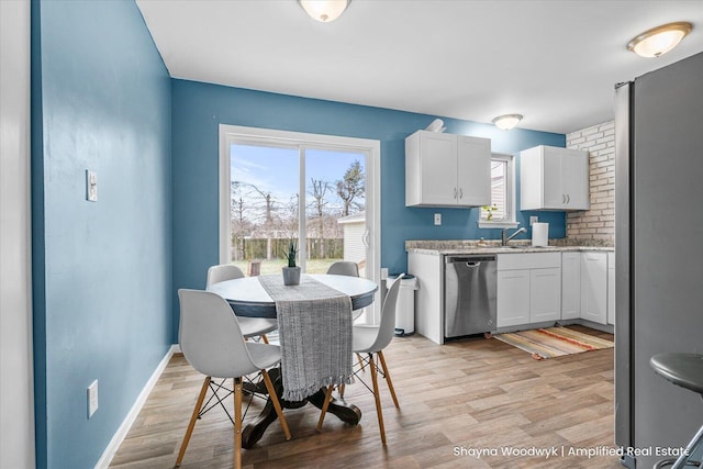 dining space featuring light wood-type flooring and baseboards