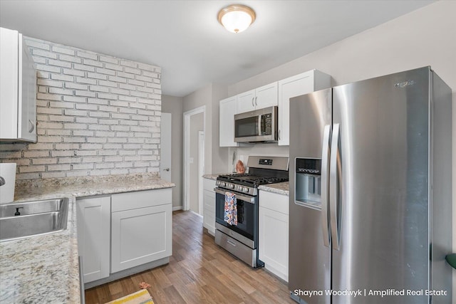 kitchen with stainless steel appliances, light wood-type flooring, a sink, and light countertops