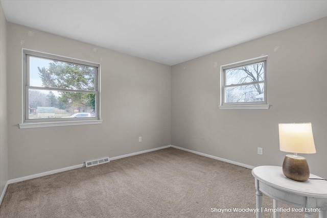 carpeted empty room featuring plenty of natural light, visible vents, and baseboards