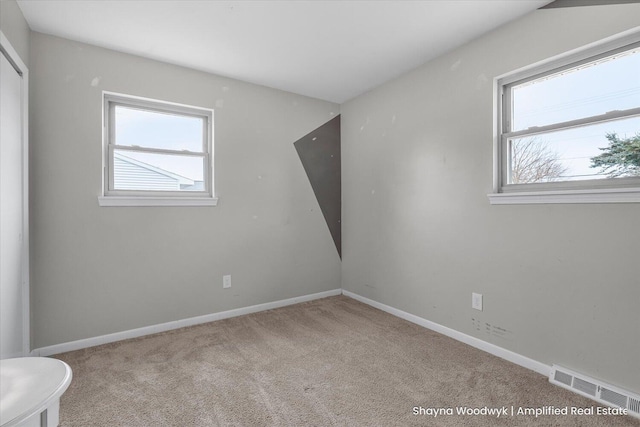 spare room with baseboards, carpet floors, visible vents, and a healthy amount of sunlight