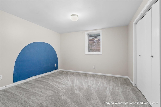 unfurnished bedroom featuring carpet, baseboards, and a closet