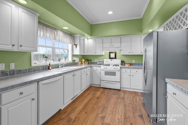 kitchen with white appliances, a sink, and white cabinets