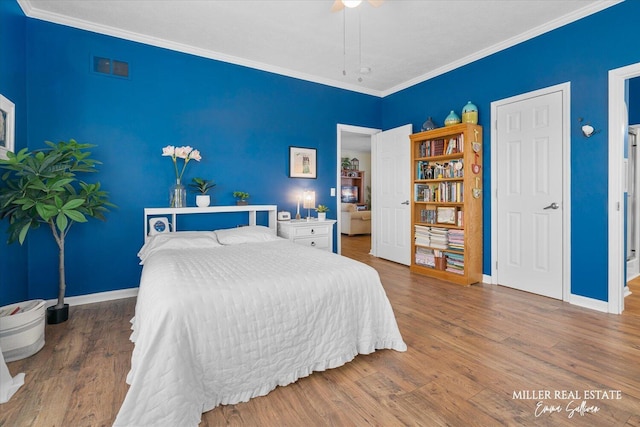 bedroom featuring visible vents, baseboards, a ceiling fan, wood finished floors, and crown molding