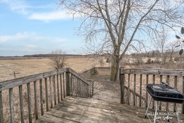 wooden deck with a rural view and a grill