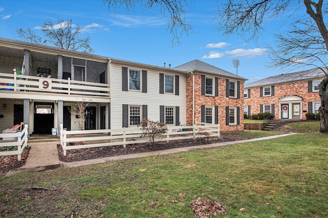 view of front of home featuring a front yard, brick siding, and fence