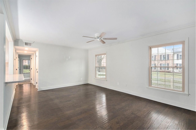 spare room featuring plenty of natural light, dark wood finished floors, visible vents, and crown molding