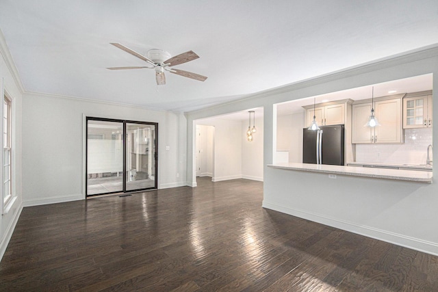 unfurnished living room with baseboards, dark wood finished floors, a ceiling fan, crown molding, and a sink