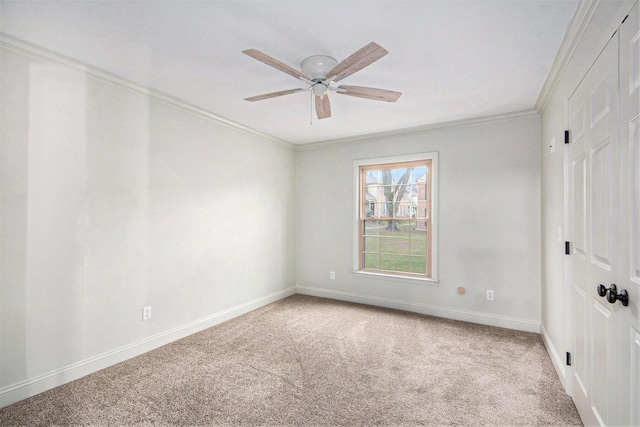 empty room featuring ornamental molding, carpet flooring, baseboards, and a ceiling fan