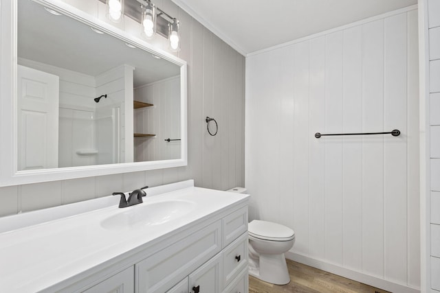 bathroom with toilet, wood finished floors, walk in shower, crown molding, and vanity