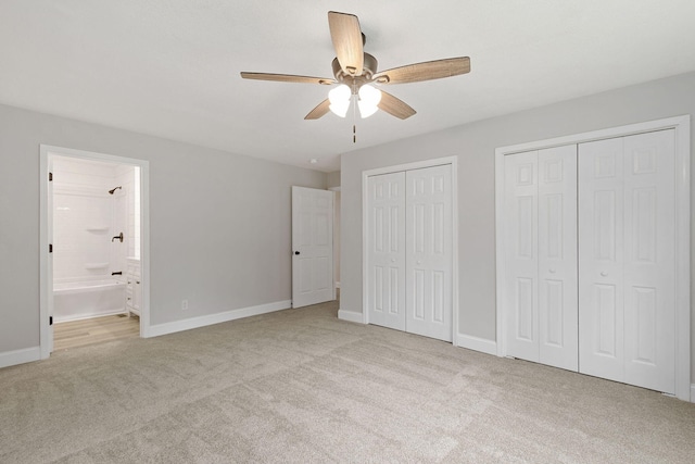 unfurnished bedroom featuring ceiling fan, two closets, baseboards, carpet, and ensuite bath