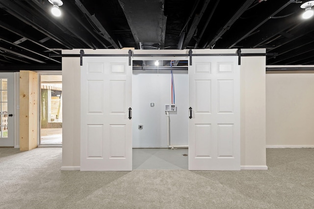 basement with carpet, baseboards, and a barn door