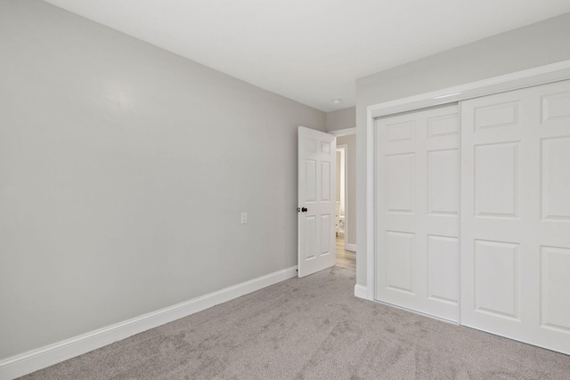 unfurnished bedroom featuring a closet, carpet flooring, and baseboards