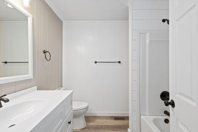 bathroom with toilet, washtub / shower combination, vanity, wood finished floors, and baseboards