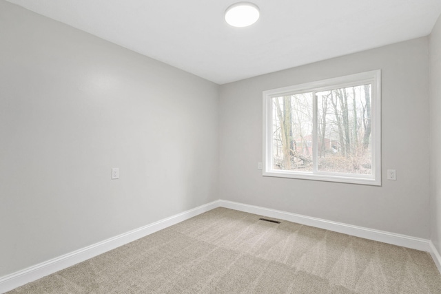 carpeted empty room featuring visible vents and baseboards