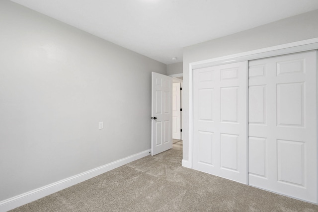 unfurnished bedroom featuring carpet, baseboards, and a closet