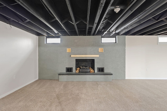 basement with carpet floors, a fireplace, visible vents, and a healthy amount of sunlight