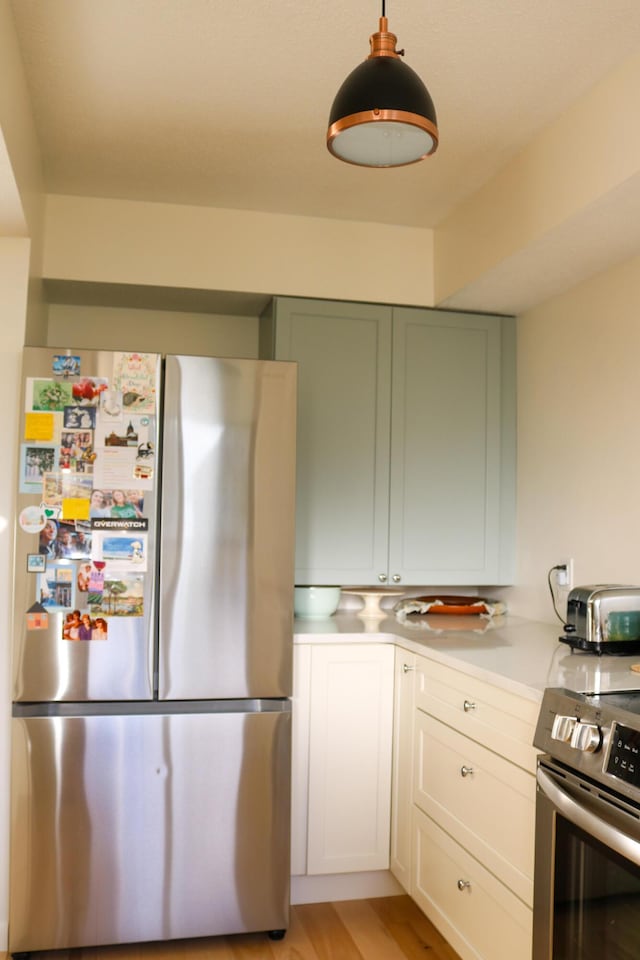 kitchen with stainless steel appliances, a toaster, light countertops, and light wood-style floors