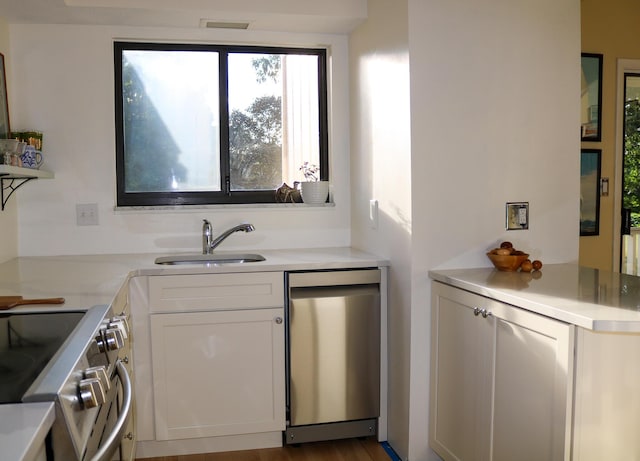 kitchen with white cabinets, stainless steel appliances, a sink, and light countertops