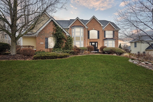 traditional-style home featuring a front yard and brick siding