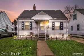 bungalow-style house with a chimney and a front yard