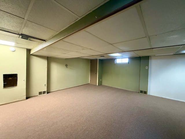 basement featuring carpet floors, visible vents, and a paneled ceiling