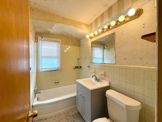 bathroom with toilet, tile patterned floors, bathtub / shower combination, vanity, and tile walls