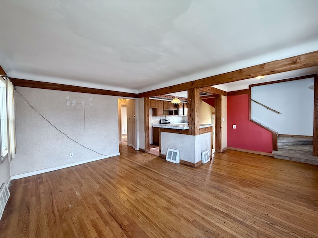 unfurnished living room featuring wood finished floors, visible vents, and baseboards