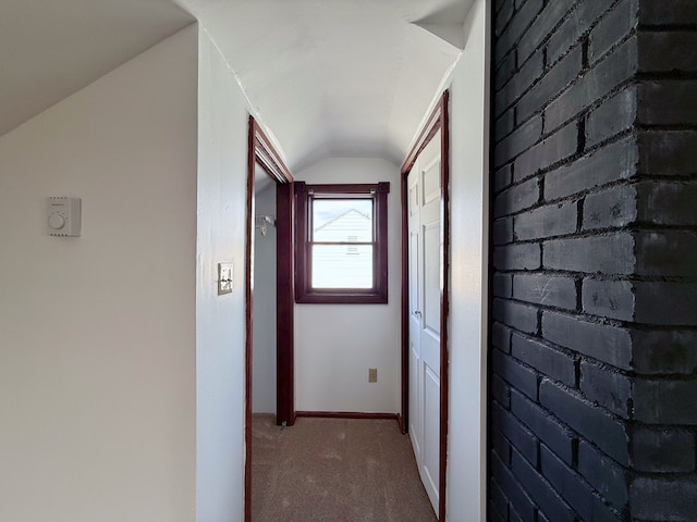 hallway with carpet, brick wall, vaulted ceiling, and baseboards