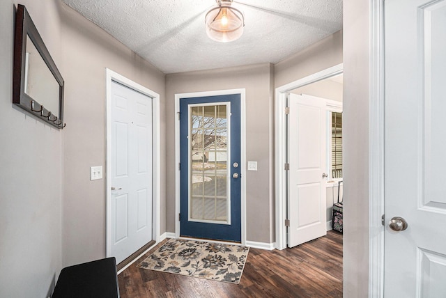 foyer entrance with dark wood-style floors, baseboards, and a textured ceiling