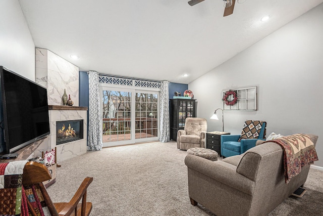 living area featuring vaulted ceiling, ceiling fan, a fireplace, and carpet flooring