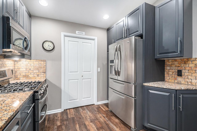 kitchen featuring baseboards, appliances with stainless steel finishes, dark wood-style flooring, light stone countertops, and backsplash